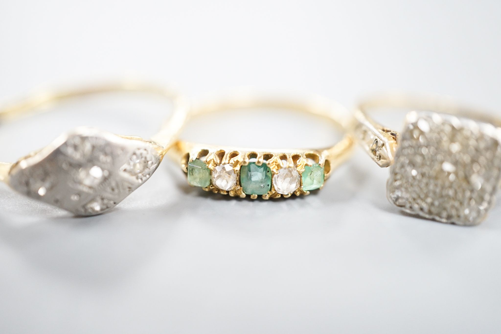 Two 18ct, plat. and diamond chip set dress rings and an 18ct, emerald and diamond set five stone ring, sizes P,I and H/I, gross weight 6 grams.